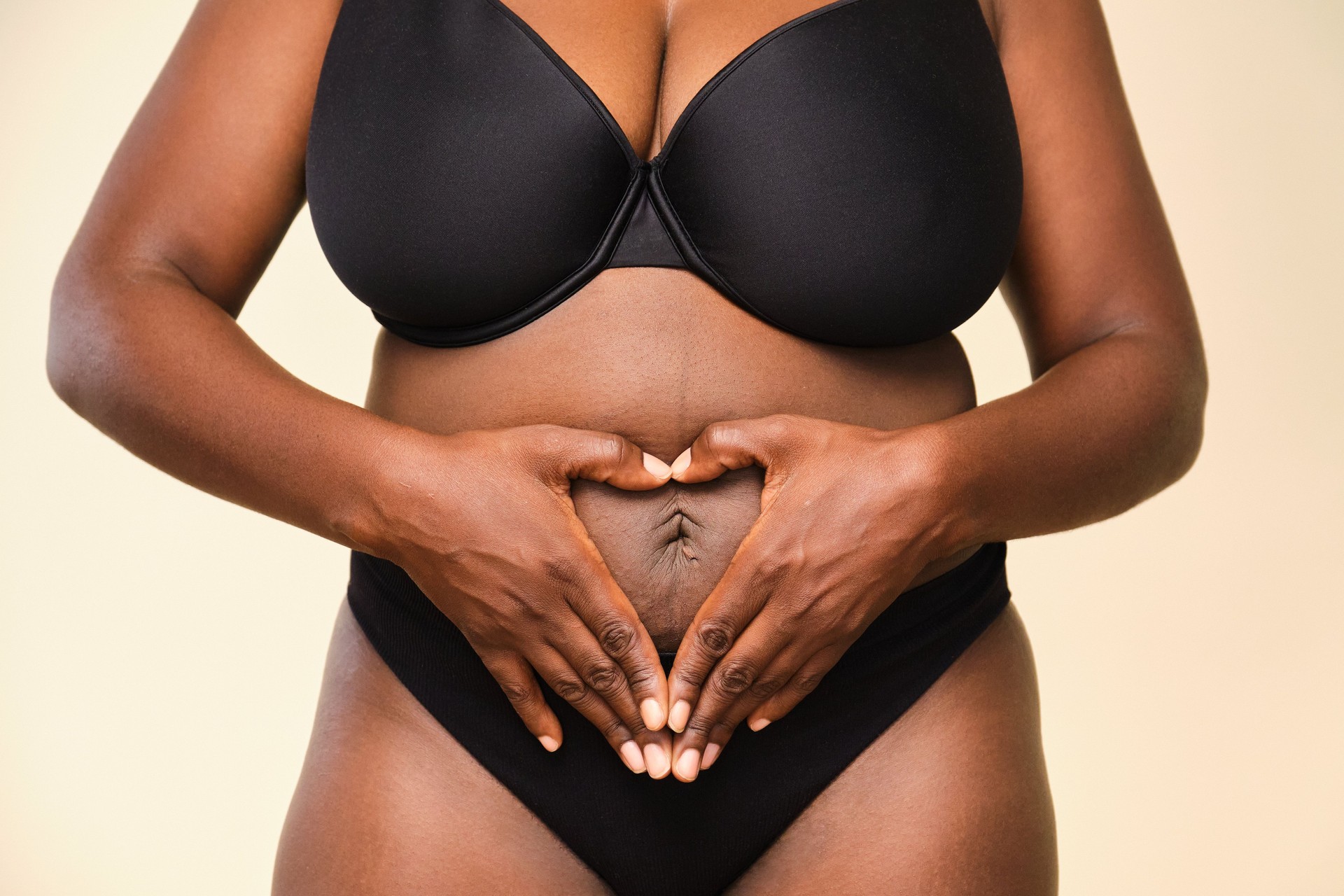 Woman making heart shape with hands on her belly