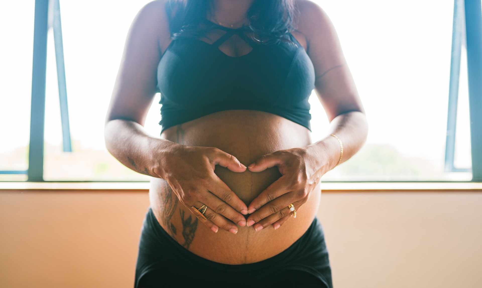 Pregnant woman making heart shape on her bump.