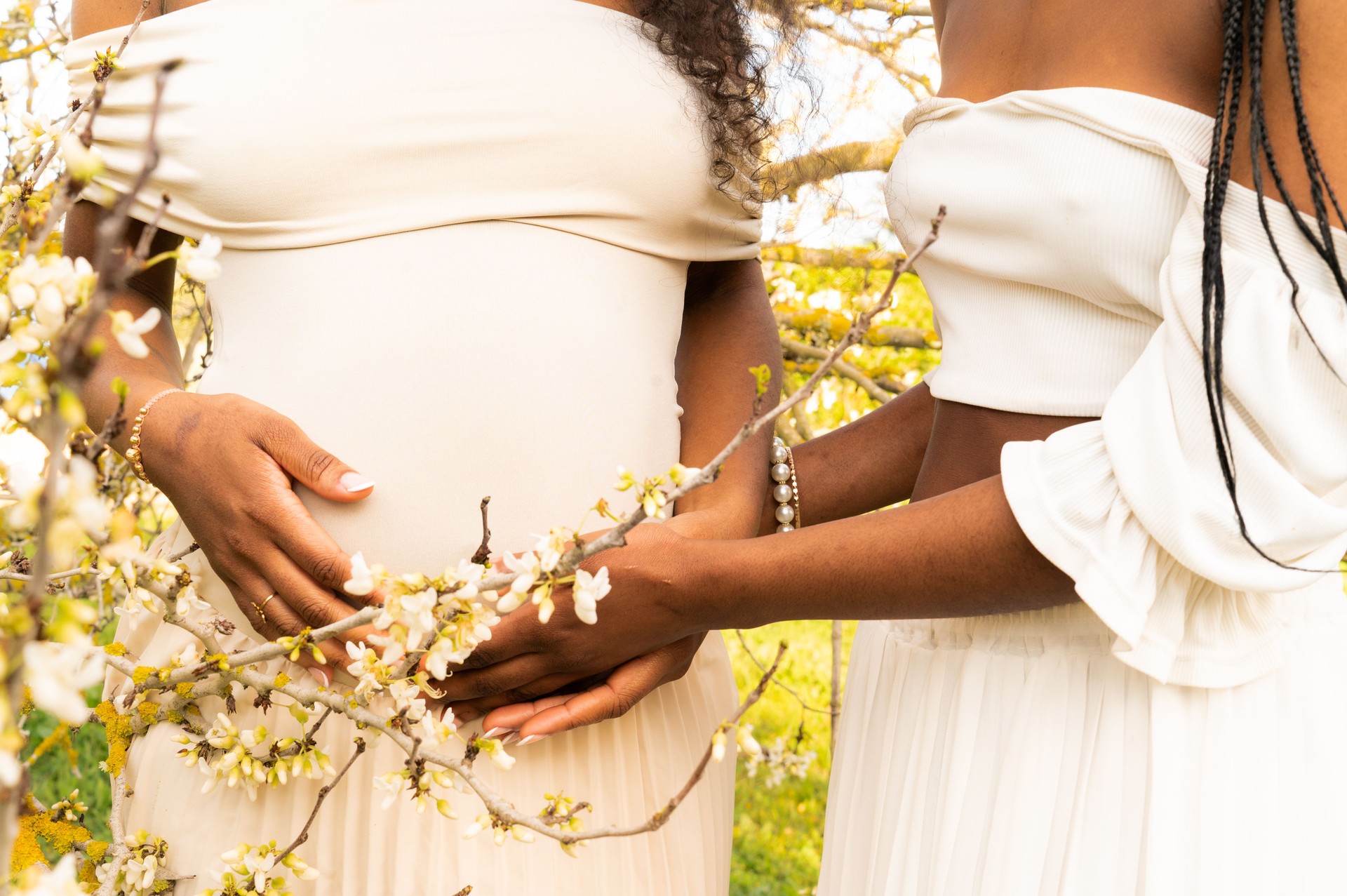 Two women sharing a tender moment with blooming flowers and pregnancy in nature Two women sharing a tender moment with blooming flowers and pregnancy in nature